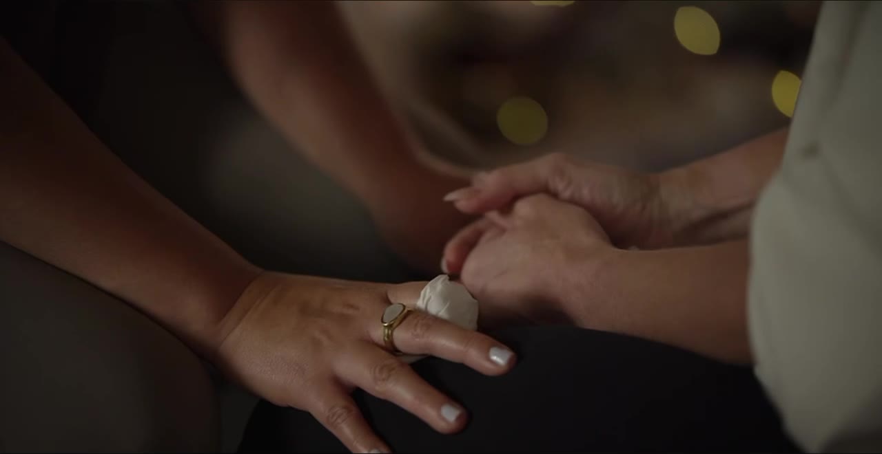 Two women's hands, one holding the other.