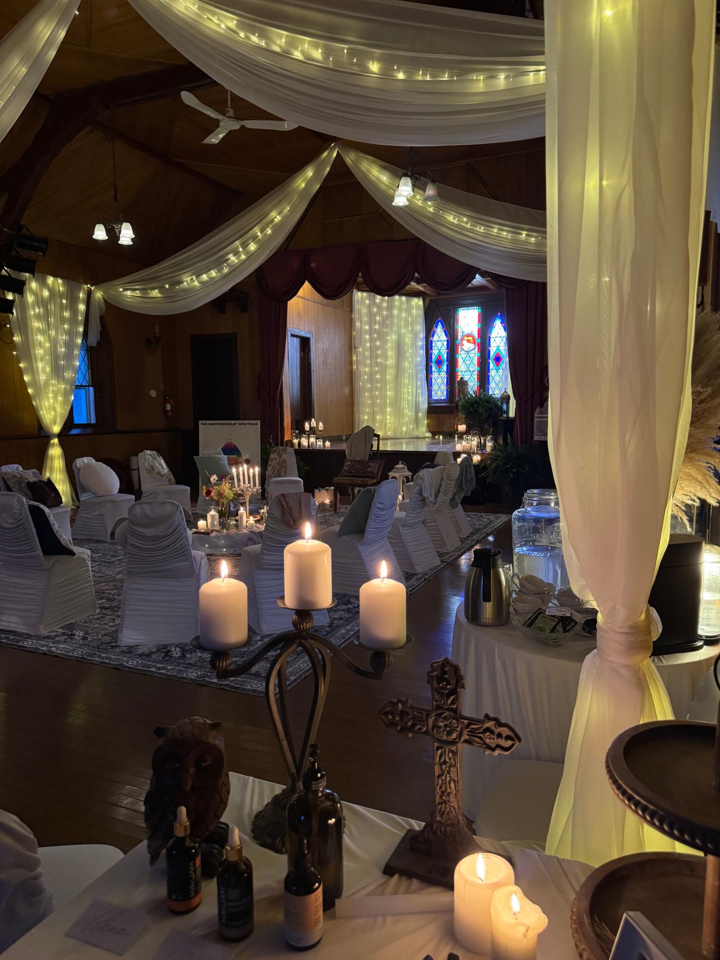 The gathering room on the first night: draped lights, candles, white chairs circling a candlelit altar.