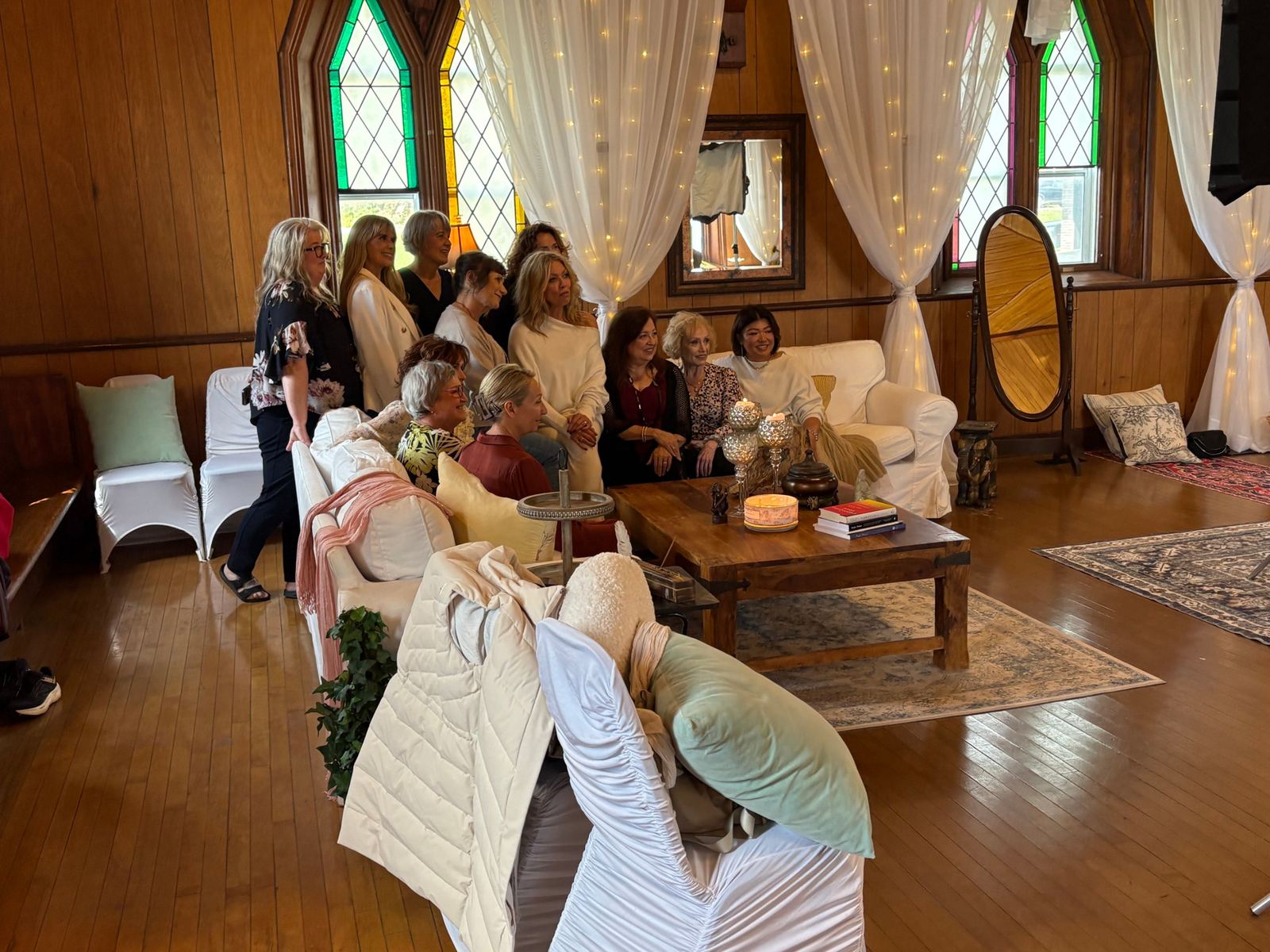The women of the first gathering together on white sofas beneath stained-glass windows.